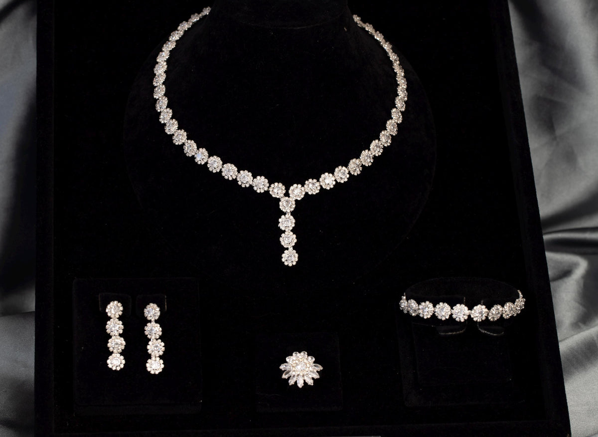 Angled view of a floral Y necklace with matching drop earrings, bracelet and flower ring in a black velvet display.