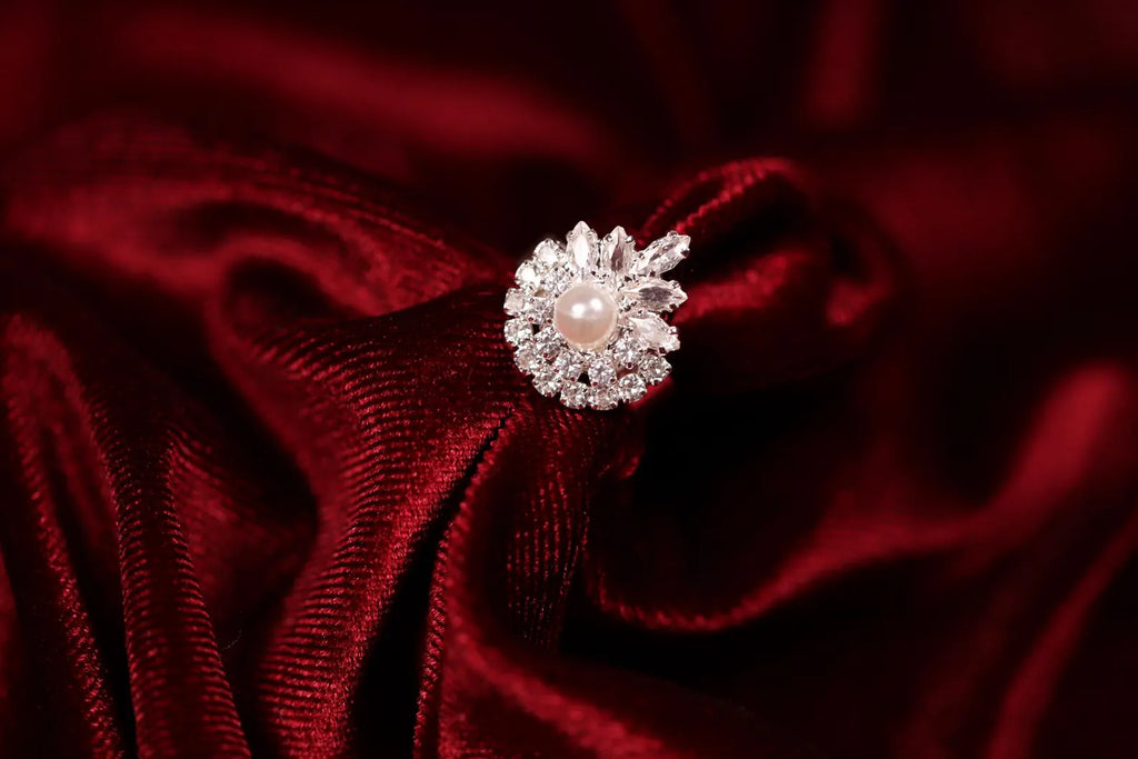 Adjustable silver floral cubic zirconia statement ring displayed on red satin