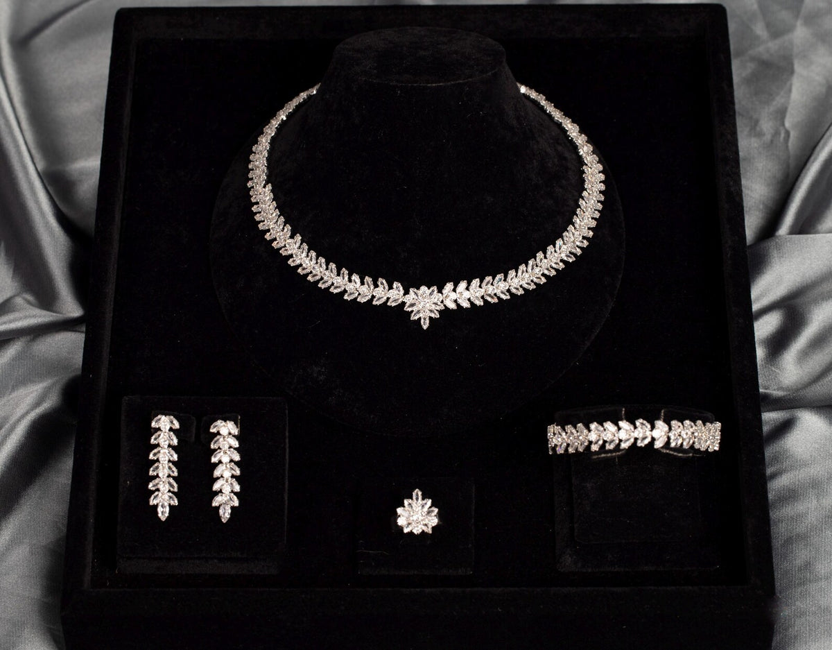 Front view of a leaf and flower zircon jewelry set in a black velvet box framed by silver-gray satin.