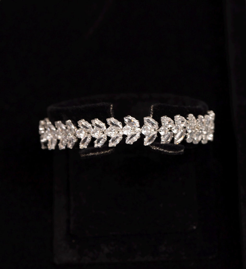 Close-up of a silver-tone zircon bracelet featuring a continuous pattern of paired leaf motifs.