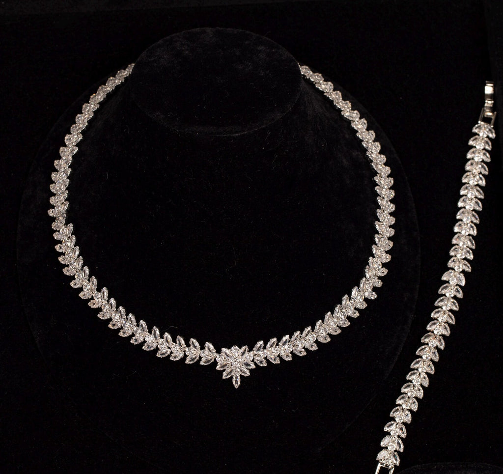 Leaf and flower zircon necklace beside its matching leaf bracelet, showing the coordinated botanical design on black velvet.
