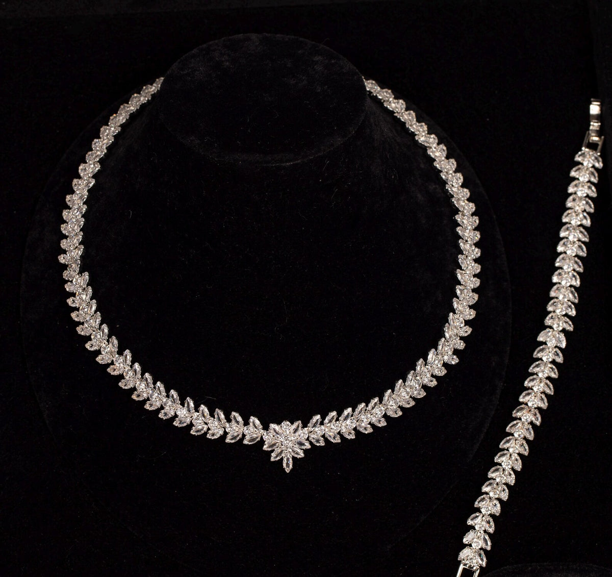Leaf and flower zircon necklace beside its matching leaf bracelet, showing the coordinated botanical design on black velvet.