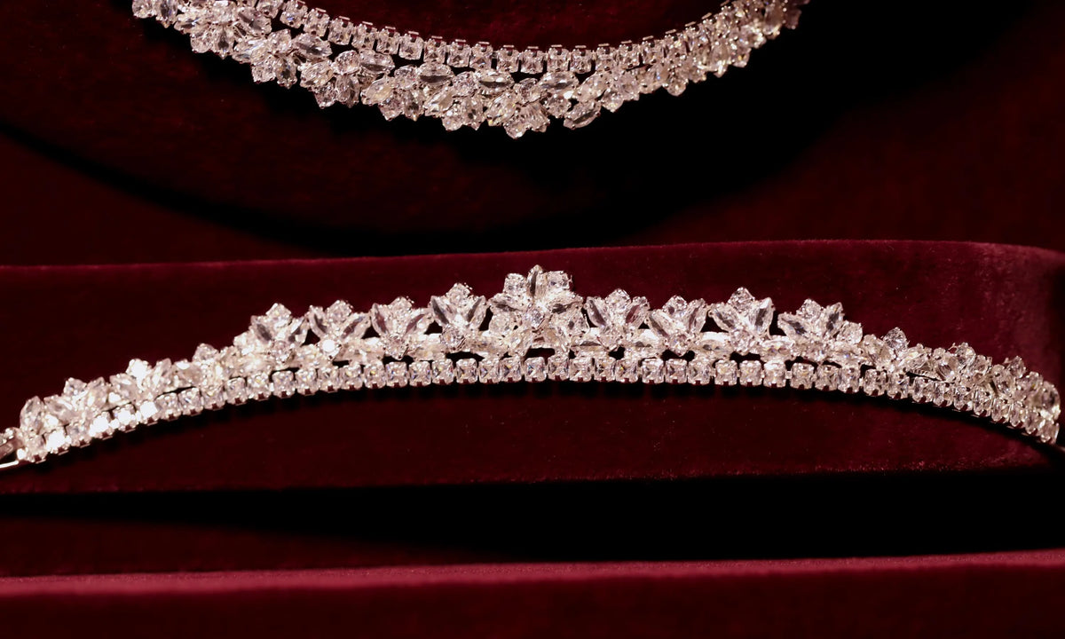 Close-up of a silver-tone zircon bracelet with raised floral motifs and a sparkling stone border on burgundy velvet.