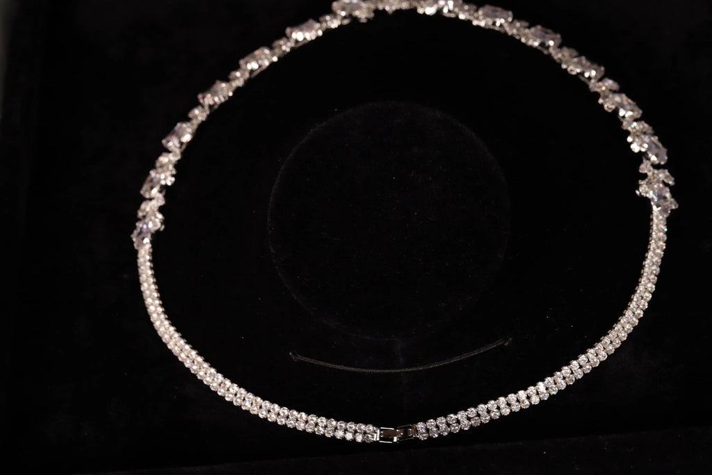 Silver-tone necklace arranged in a circle on black velvet, showing its decorative back and slender stone-set chain