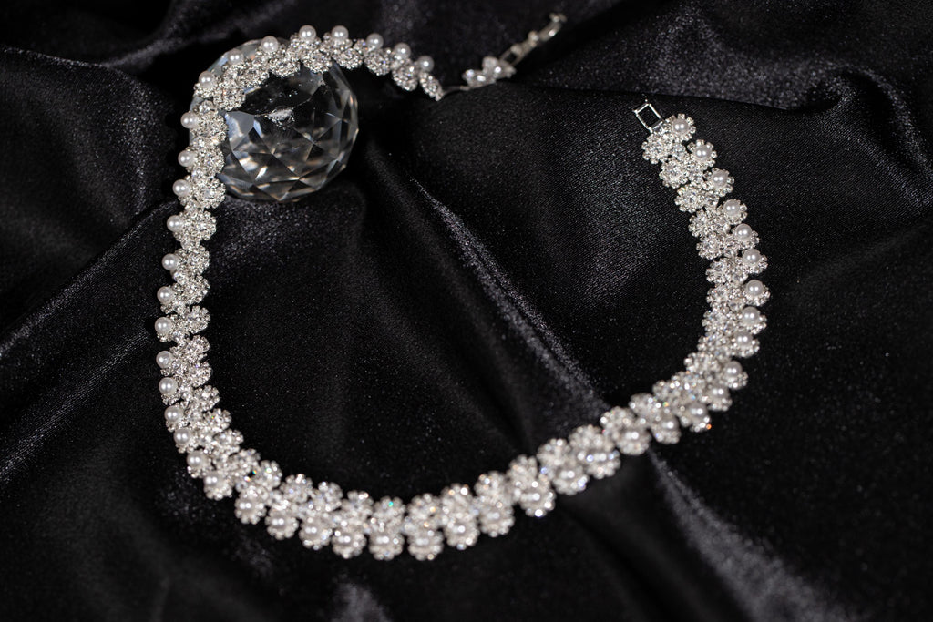Floral faux pearl bridal necklace arranged on black satin, showing its curved shape and delicate zircon flower details.