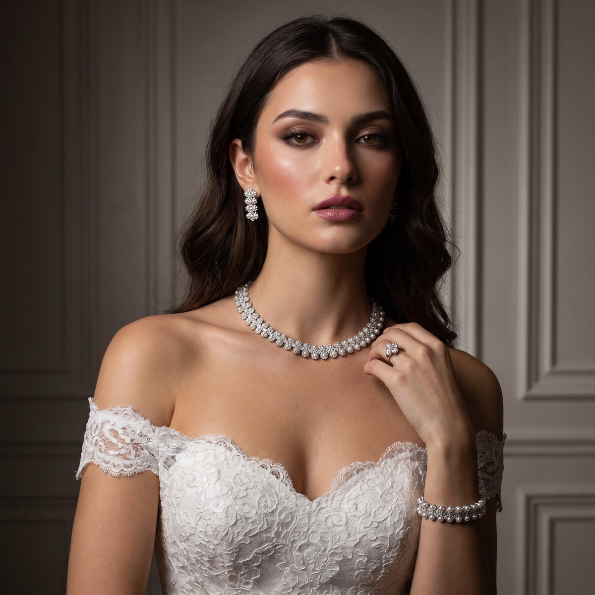 Bride touching a dainty floral and faux pearl necklace, wearing matching earrings and bracelet with a lace wedding dress.