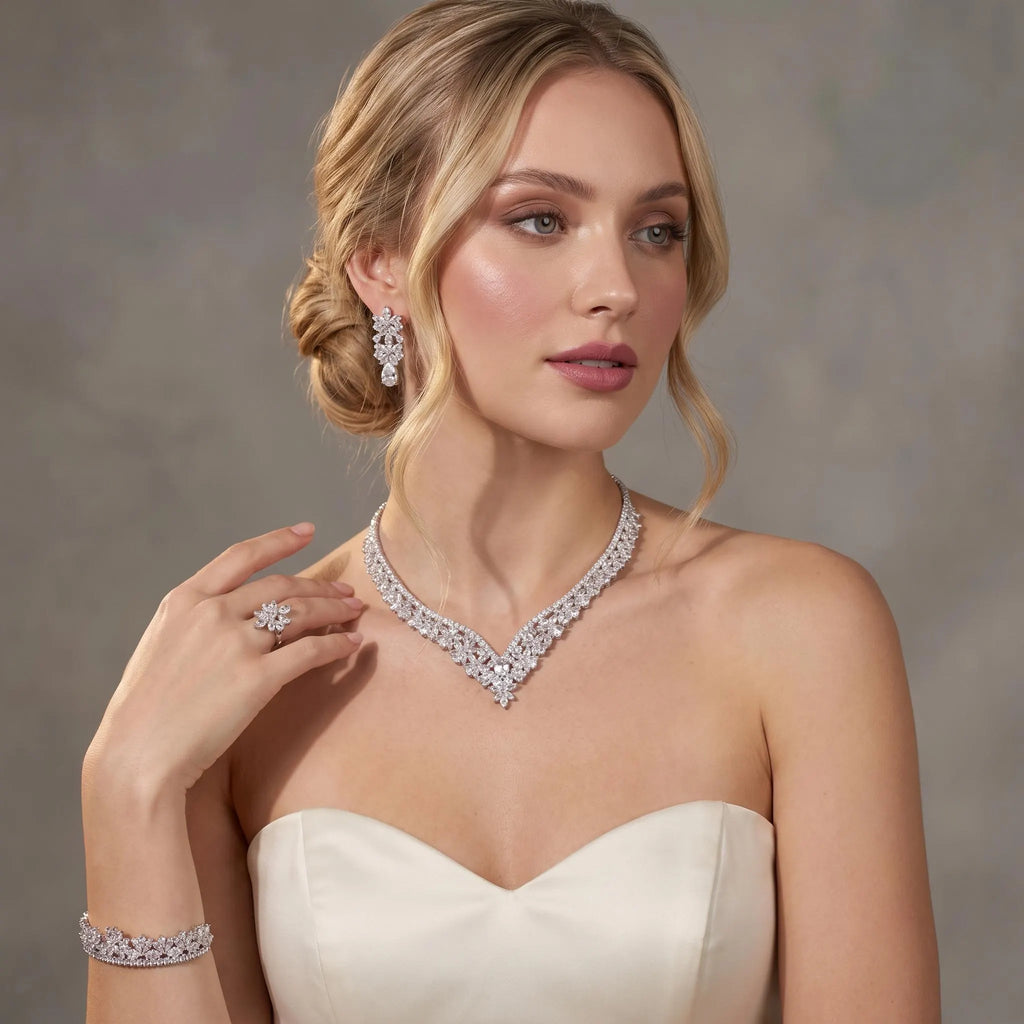Bride in a sweetheart gown wearing a silver-tone floral V necklace with coordinating earrings, bracelet and ring.