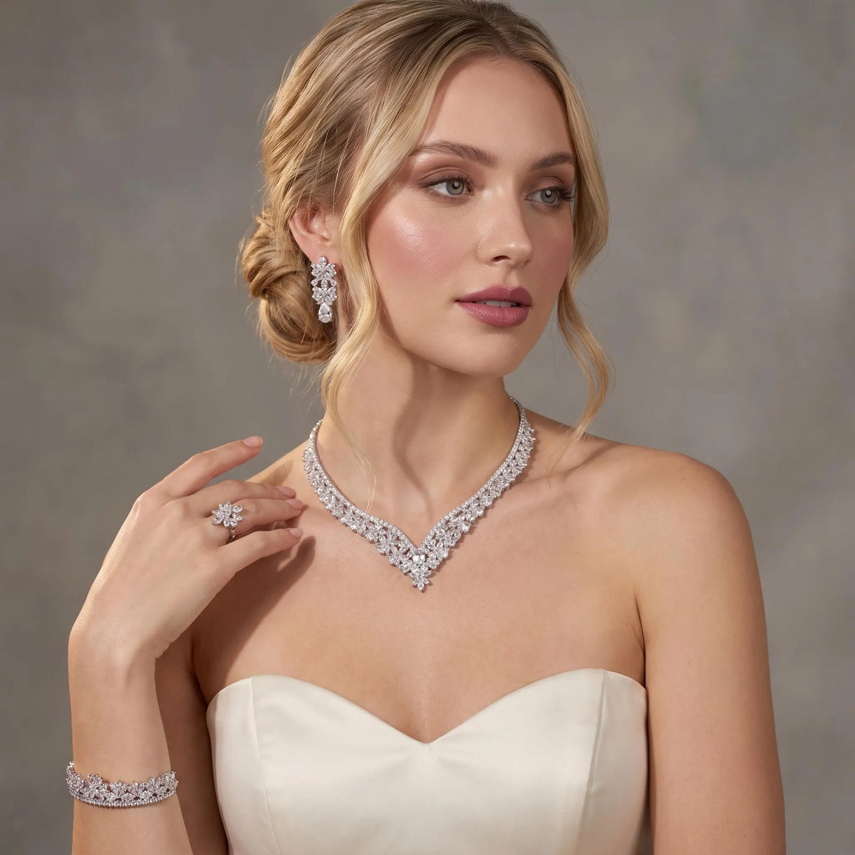 Bride in a sweetheart gown wearing a silver-tone floral V necklace with coordinating earrings, bracelet and ring.