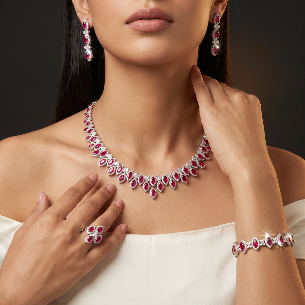 Close-up of a model wearing a red zircon necklace, drop earrings, bracelet and statement ring with an ivory evening dress.