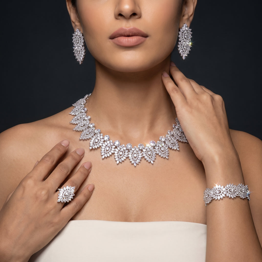 Model wearing a silver-tone bridal jewelry set with an ornate marquise-motif necklace, drop earrings, bracelet and ring
