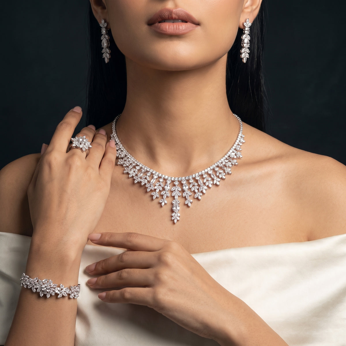 Model wearing a silver-tone floral bridal jewelry set with a cascading teardrop necklace, drop earrings, bracelet and ring.