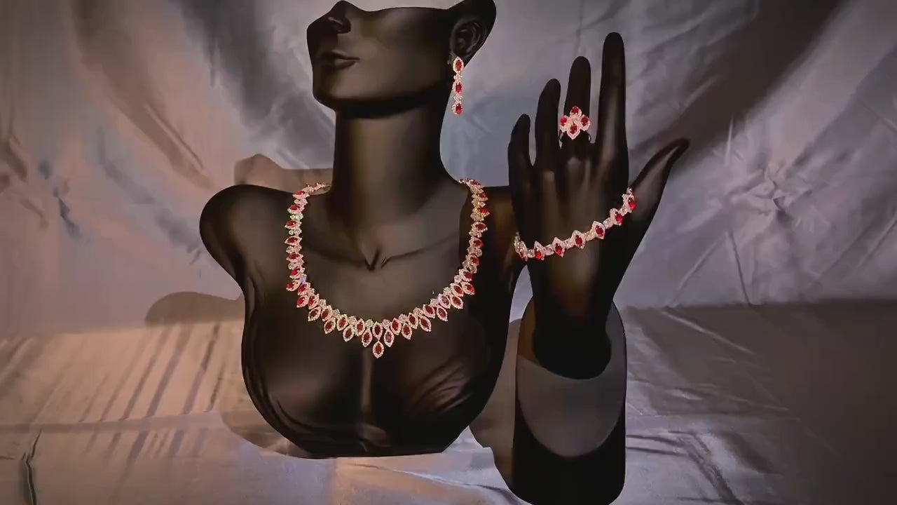 Red zircon necklace, drop earrings, bracelet and ring displayed on black jewelry stands against a satin backdrop.
