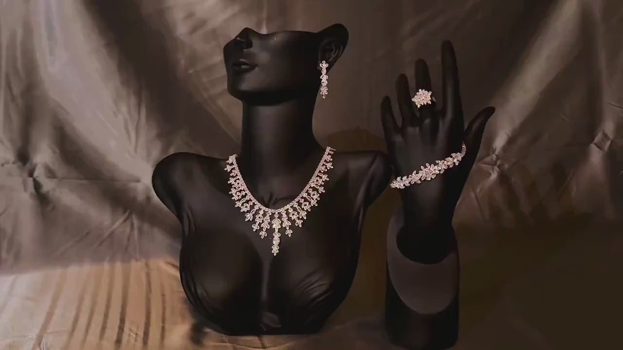 Floral bridal jewelry set displayed on a black bust and hand stand, featuring a cascading necklace and matching accessories.