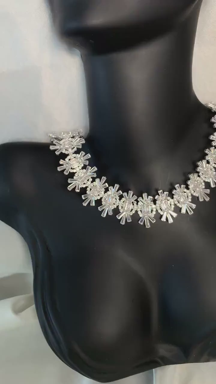 Silver crystal statement necklace displayed on a black jewelry mannequin