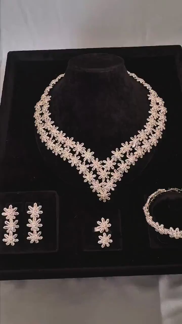 Silver floral bridal jewelry set displayed on black velvet with matching necklace, earrings, bracelet and ring