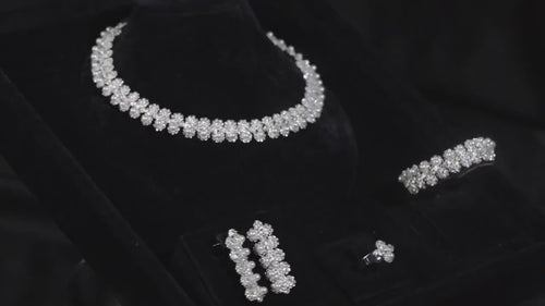 Silver-tone floral and faux pearl bridal jewelry set displayed on black velvet, with matching necklace, earrings, bracelet and ring.