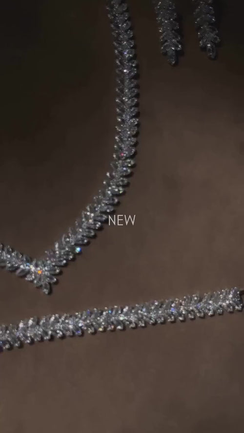 Close-up of a silver-tone zircon necklace with leaf motifs and a floral centerpiece, shown with matching jewelry.